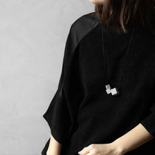 Load image into Gallery viewer, A woman with a blond hair wearing the Grey MODULOTRE Necklace with a black bluse on a grey background
