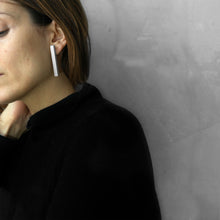Load image into Gallery viewer, A woman wearing the Grey Column Earrings with a black bluse on a grey background