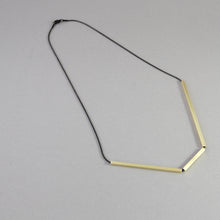 Laden Sie das Bild in den Galerie-Viewer, Minimalist architectural necklace featuring geometric gold bars suspended on a black cord.