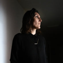 Laden Sie das Bild in den Galerie-Viewer, Minimalist geometric necklace styled against contemporary architecture and contrasting shadows.