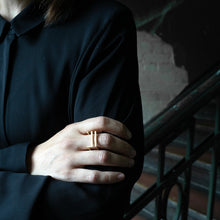 Laden Sie das Bild in den Galerie-Viewer, Contemporary square statement ring worn in an urban environment with contrasting light and shadow patterns.