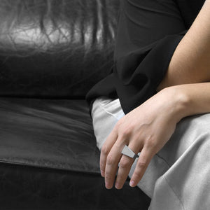 a person wearing the the aluminum square ring model 05 while she are setting on a black sofa