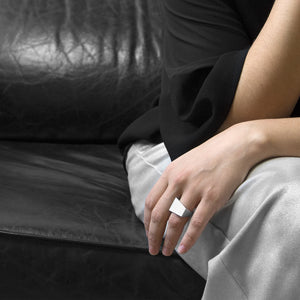 a person wearing the the aluminum square ring model 06 while she are setting on a black sofa