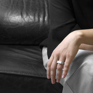 a person wearing the the aluminum square ring model 4 while she are setting on a black sofa