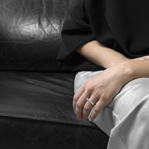  a person wearing the the aluminum square ring model 1 while she are setting on a black sofa