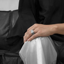 Load image into Gallery viewer, A person wearing the MK3 Ring on their ring finger while sitting on a black leather sofa