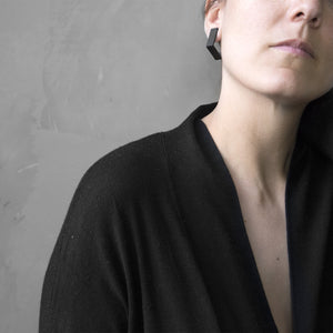 A woman wearing the Black Square Earrings with a black bluse on a grey background 