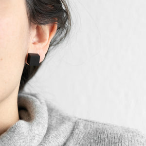 A girl is wearing the Cube earrings black 