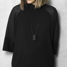 Load image into Gallery viewer, A woman with a blond hair wearing the Black Rectangle Necklace with a black bluse on a grey background