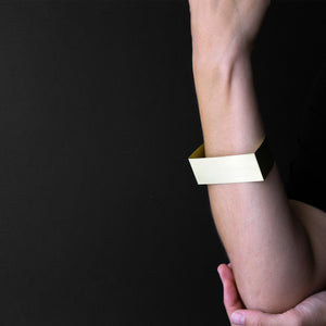 woman arm that are wearing MOON bracelet in brass with black background 