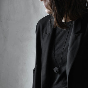 A girl wear Elemento necklace in grey version on black background