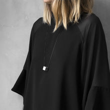 Load image into Gallery viewer, A woman with a blond hair wearing the Grey MODULOUNO Necklace with a black bluse on a grey background 