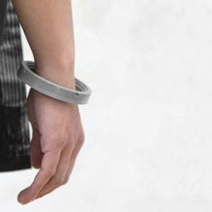 A person wearing the Black Colosseum Bangle with a grey background