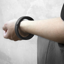 Load image into Gallery viewer, A person wearing the Black Colosseum Bangle with a grey background