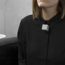 Load image into Gallery viewer, A woman with a blond hair wearing the Grey Cube Necklace with a black bluse on a grey background 