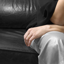 Load image into Gallery viewer, A person wearing the Brass Square Ring on their ring finger while sitting on a black leather sofa