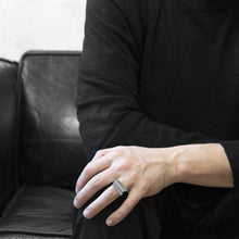 Load image into Gallery viewer, A man wearing the Assembled ring on their ring finger, a combination of 3 Aluminium square rings, while he sitting on a black leather sofa 