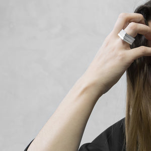A woman wearing the Assembled ring on their ring finger, a combination of 3 Aluminium square rings 