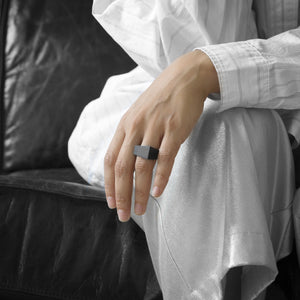 A person wearing the MK3 Ring on their ring finger while sitting on a black leather sofa